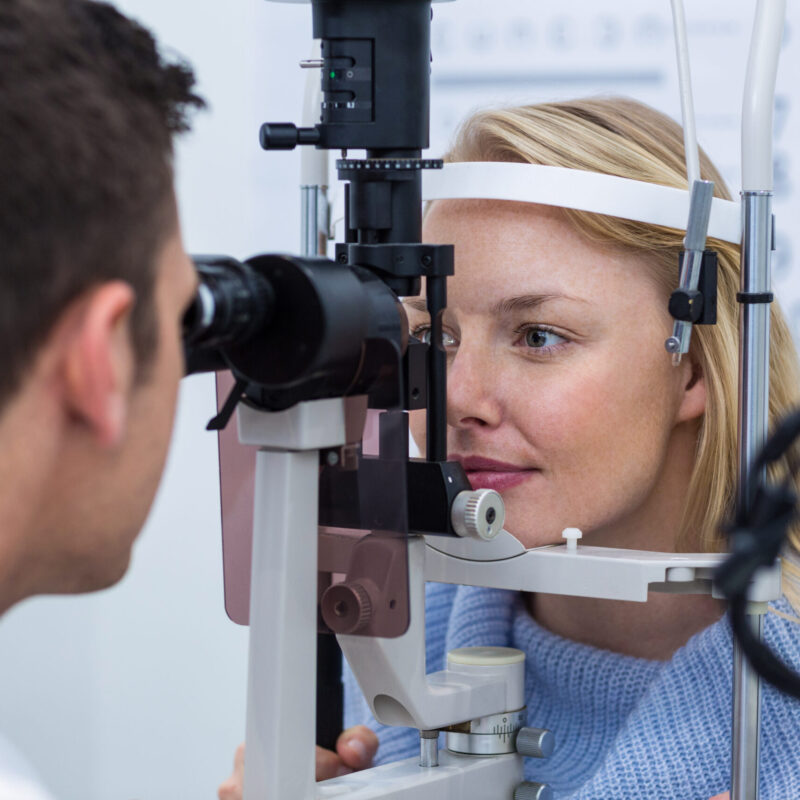 Optometrist examining female patient on slit lamp in ophthalmology clinic Optometrist examining female patient on slit lamp in ophthalmology clinic